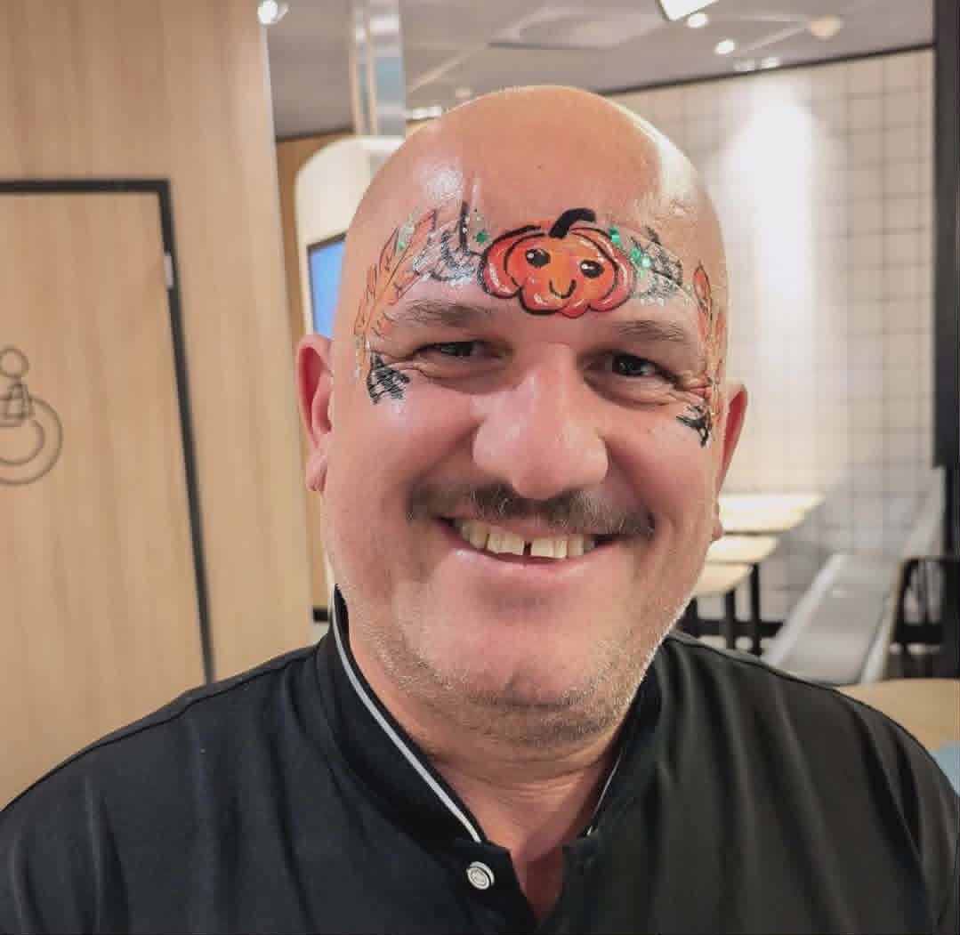 Halloween-gresskar malt over panne på smilende voksen mann