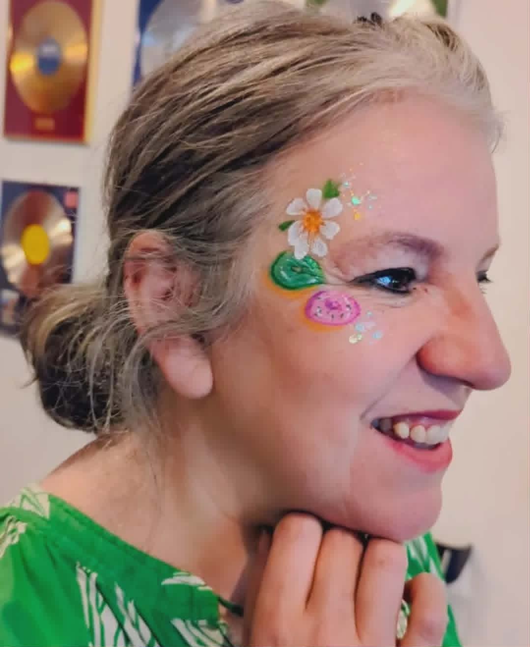 Vakker hvit blomst med glitter malt på kinn til voksen kvinne